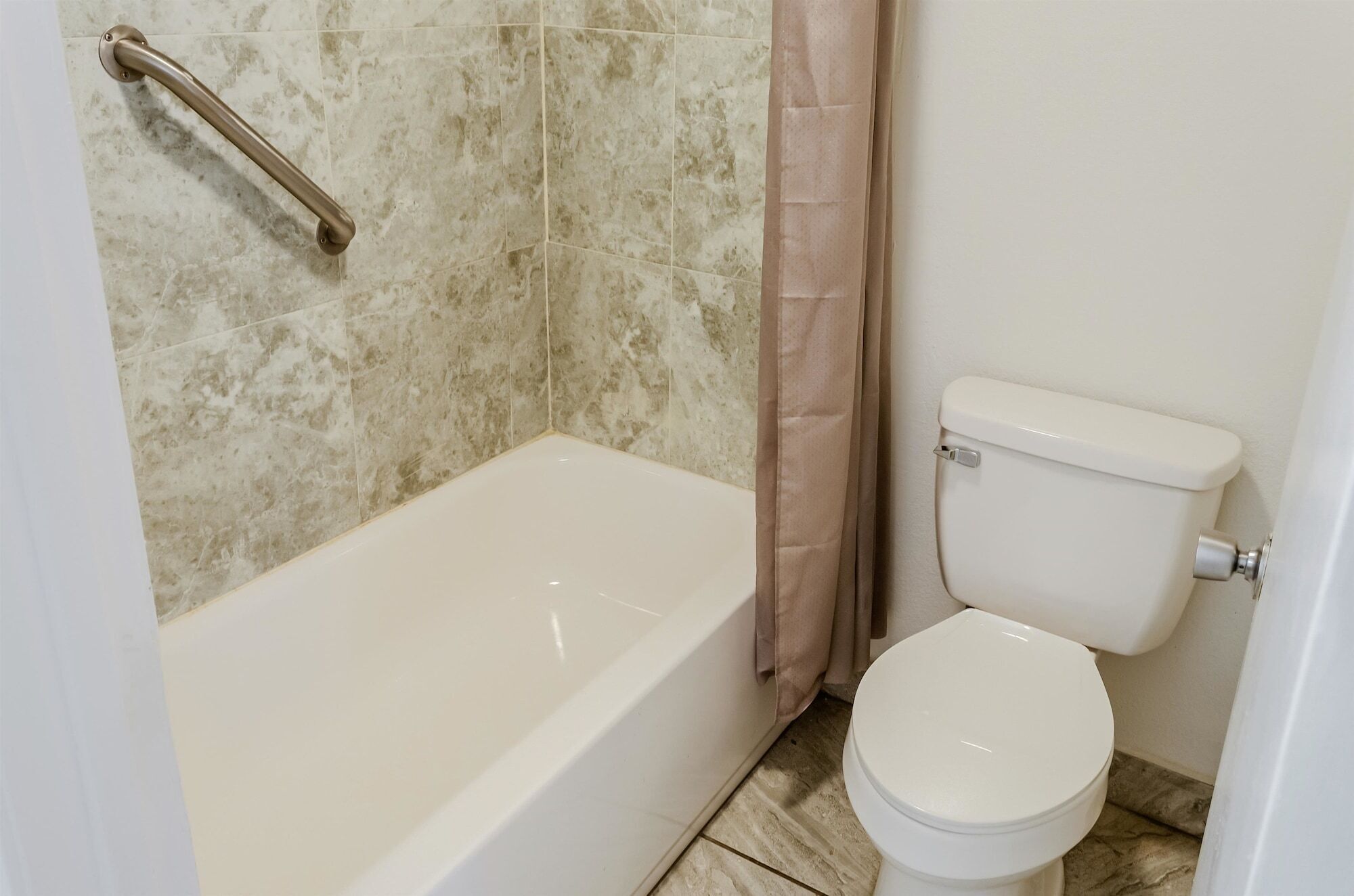 A bathroom with a bathtub, toilet, and a shower curtain.