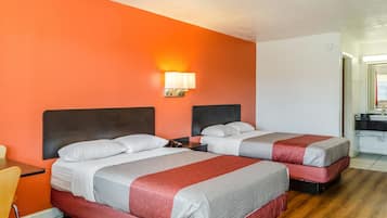 Twee bedden met hoofdborden, een nachtkastje, een lamp en een houten vloer.