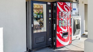 Ein Getränkeautomat mit Coca-Cola-Logo, der verschiedene Snacks und Getränke anbietet.