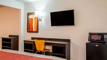 Una camera d'albergo con un letto, una scrivania, una sedia, una televisione e un forno a microonde.
