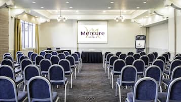 A conference room with rows of chairs, a projector screen, and a presentation area.