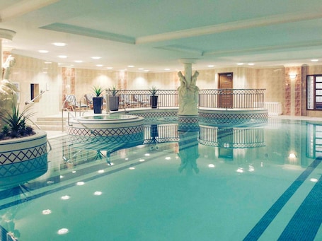 A large indoor swimming pool with multiple lanes, surrounded by lounge chairs and potted plants.. Mercure Dartford Brands Hatch Hotel & Spa