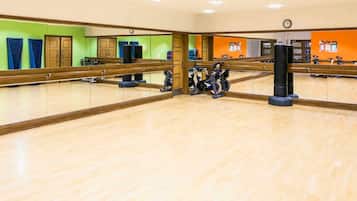 A gym with exercise equipment, a large mirror, and wooden flooring.