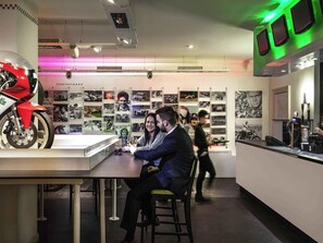 Ein modernes Interieur mit einer Motorradausstellung, einer Bar und einer Wand voller Rennmemorabilien.