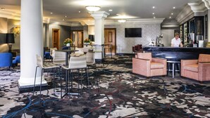 Un hall d’hôtel comprenant un comptoir d’accueil, des espaces détente et un bar.