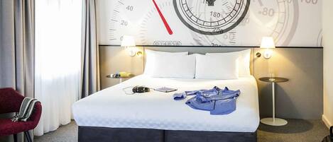 A hotel room with a large bed, two bedside tables with lamps, a red chair, and a wall clock.