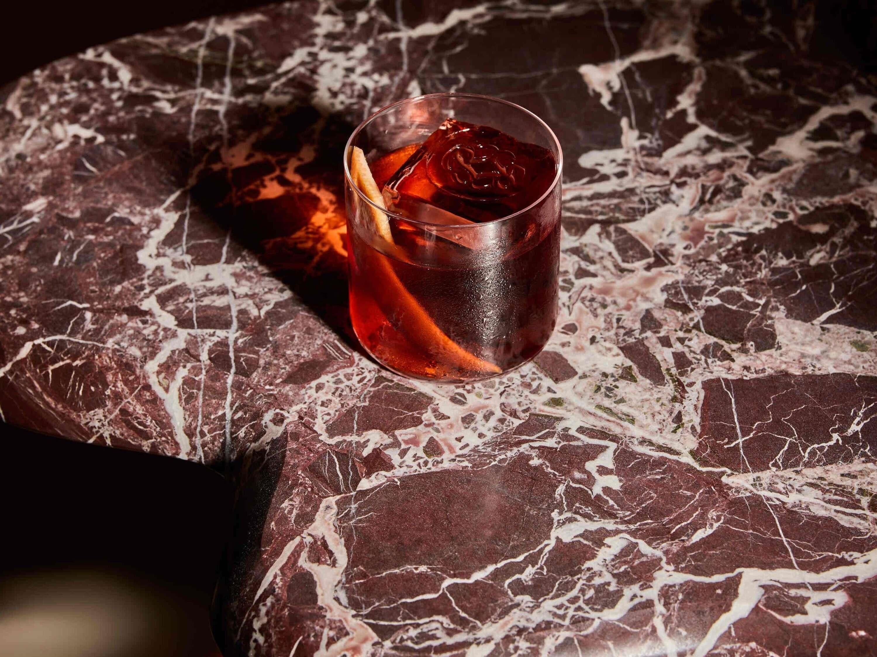 Ein Glas mit einem bernsteinfarbenen Getränk auf einer Marmorplatte.