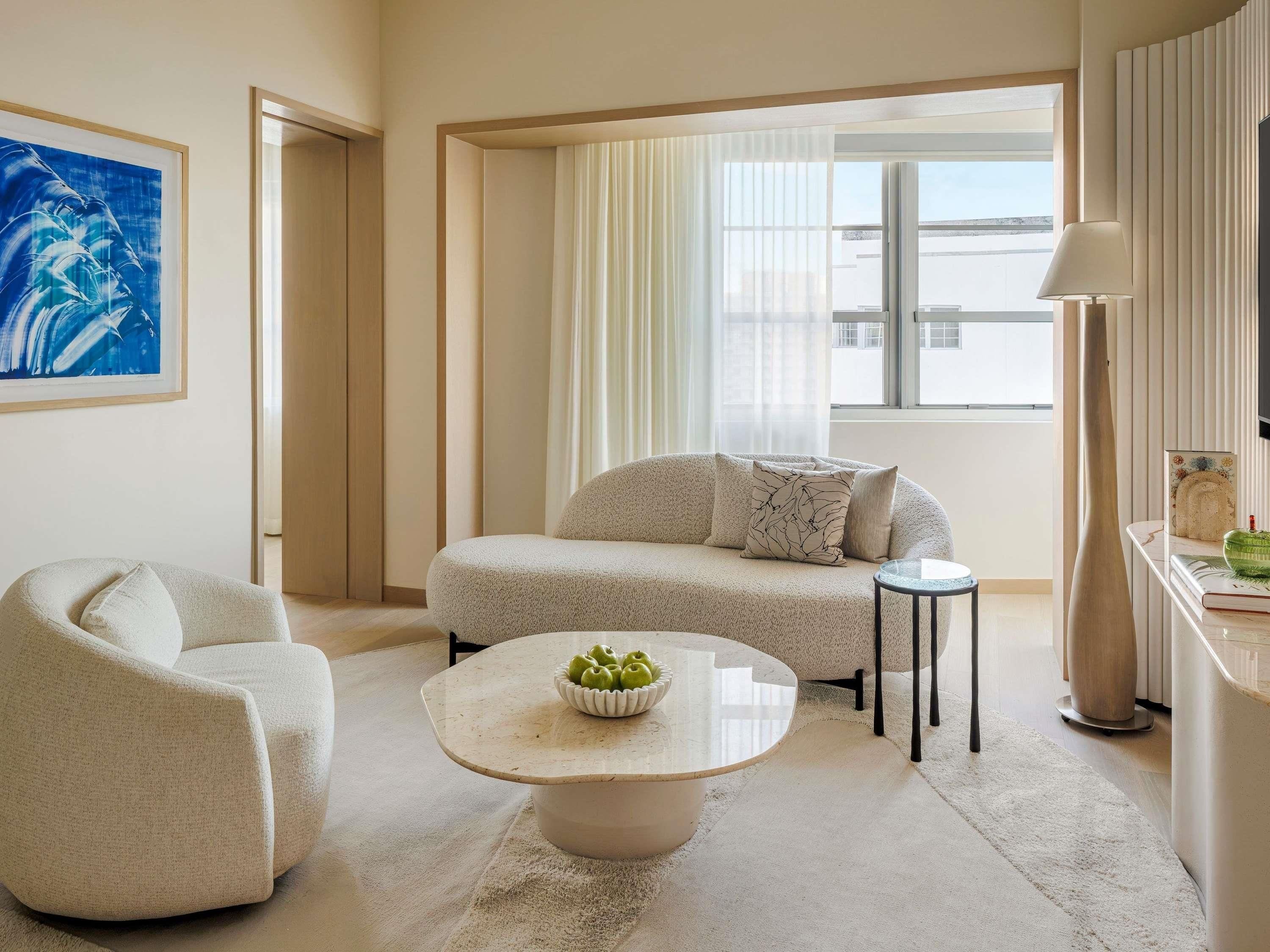 Un salon moderne avec un canapé, un fauteuil, une table basse et un tableau accroché au mur.