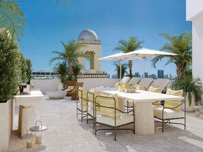 A rooftop terrace with a dining area, lounge chairs, and a view of the city skyline. - Delano Miami Beach (Miami Beach)