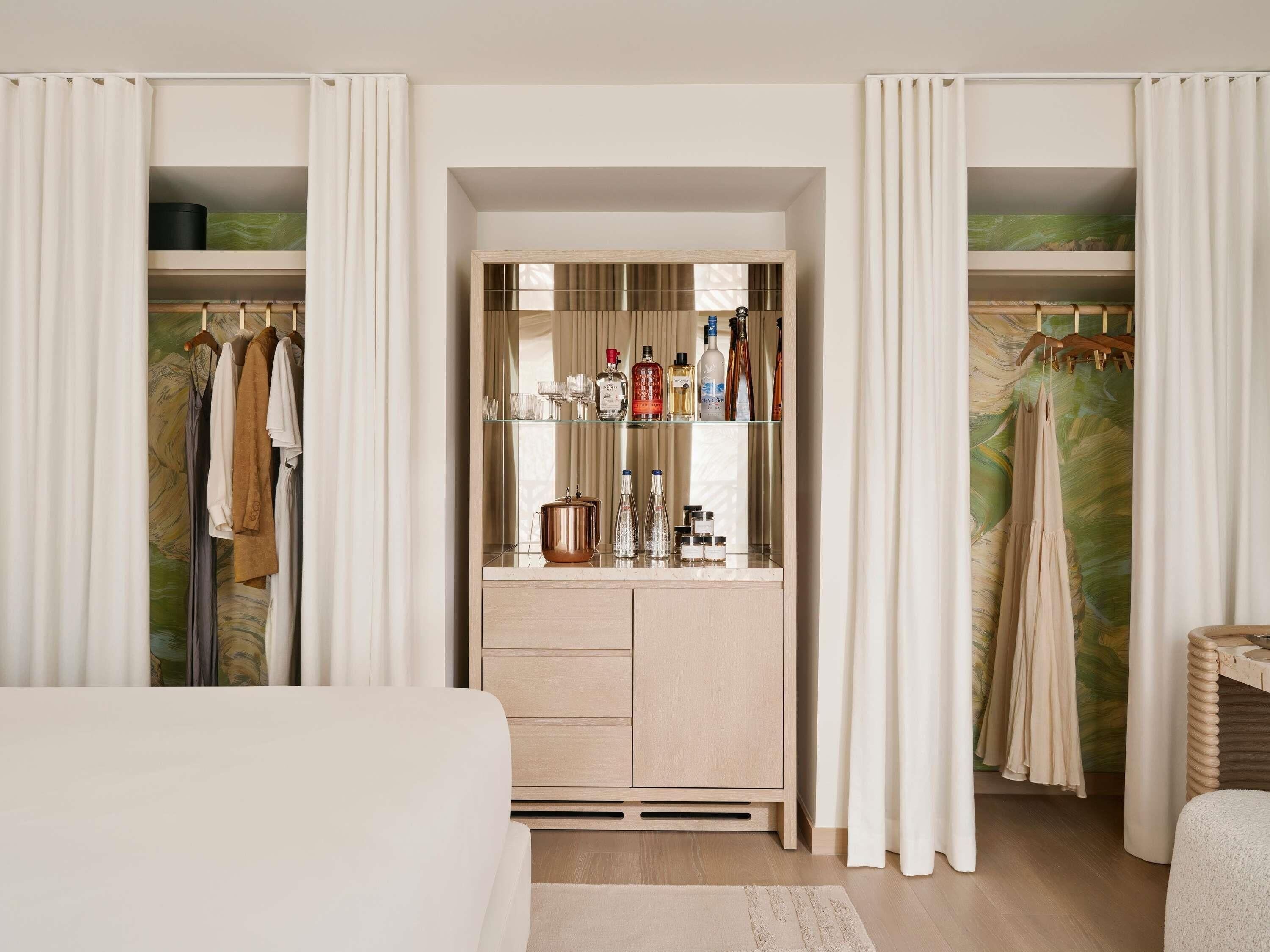 A bedroom with a bed, a dresser with drawers, a mirror, and a closet with hanging clothes.