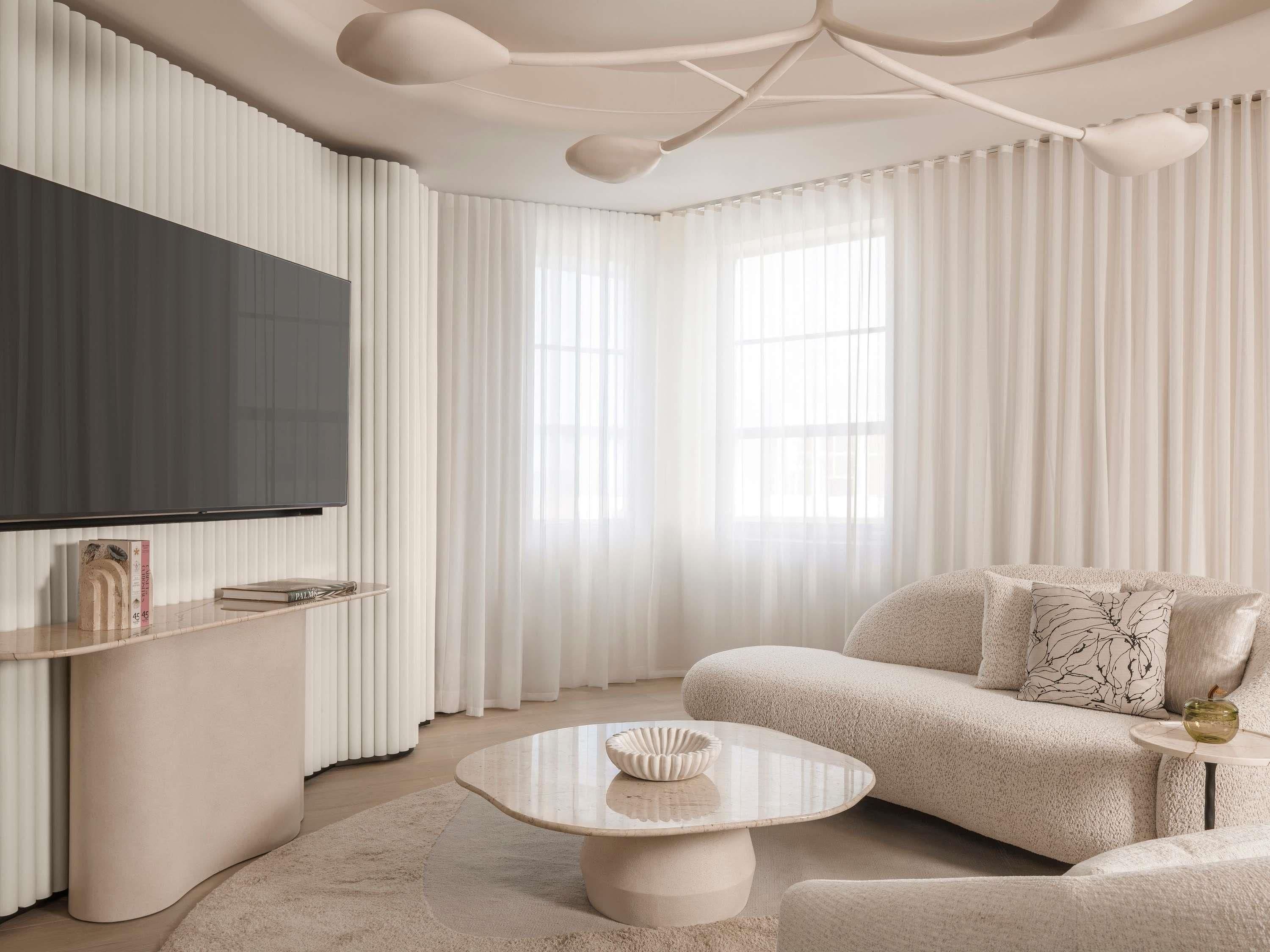 A modern living room with a flat-screen TV, a round coffee table, and a sofa.
