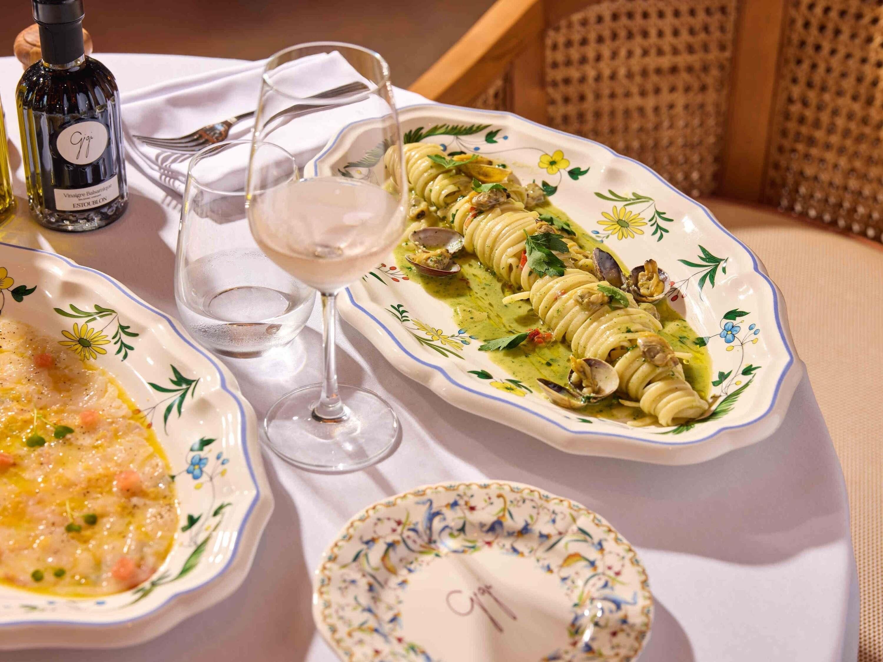 Una mesa dispuesta con platos de comida, una botella de vino y una copa de vino.