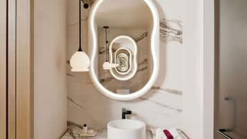 A bathroom with a marble sink, a large mirror with a light halo, pendant lights, and a towel rack.