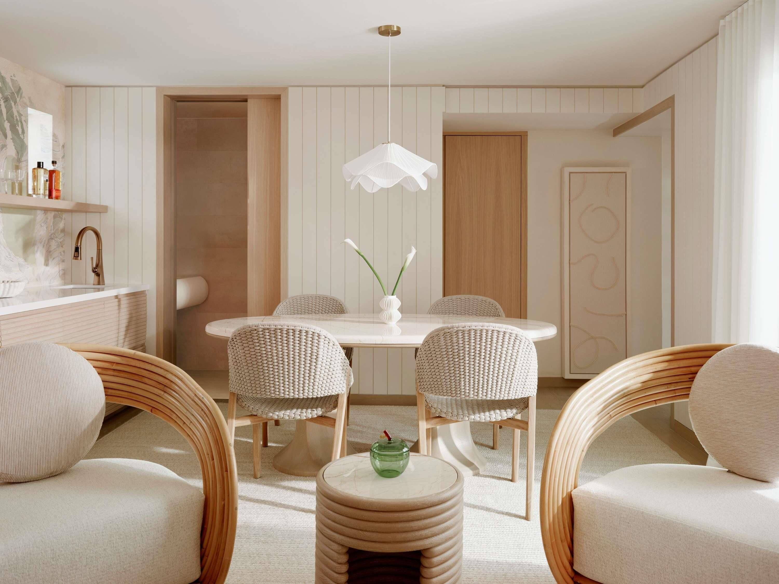 A modern dining area with wicker chairs, a white table, and a pendant light.