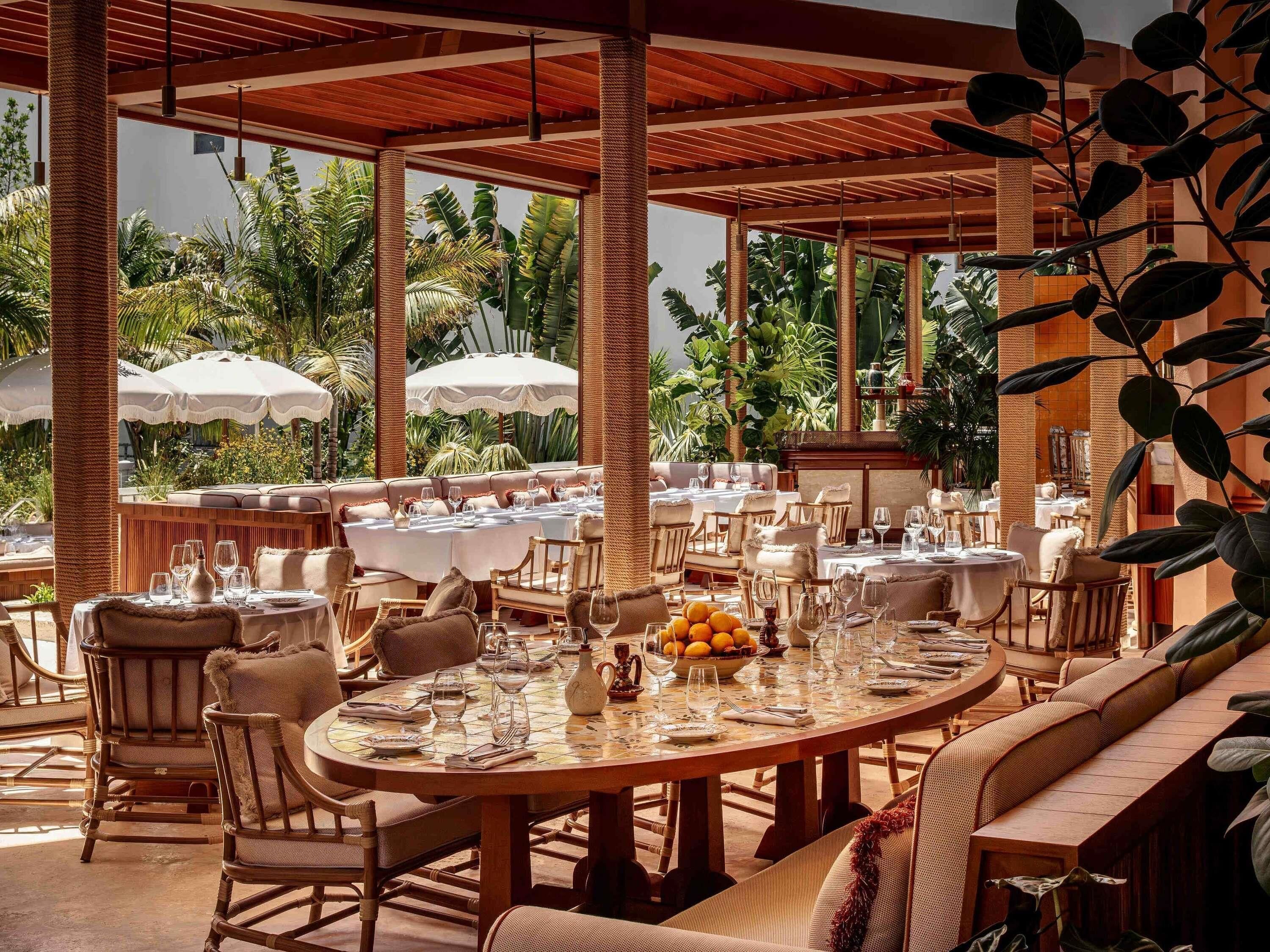 Un espace extérieur aménagé pour les repas, avec des tables rondes, des chaises et des parasols.