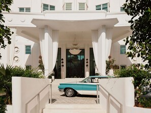 A classic car parked at the entrance of a building with a grand facade, large columns, and a staircase leading up to the entrance. - Delano Miami Beach (Miami Beach)