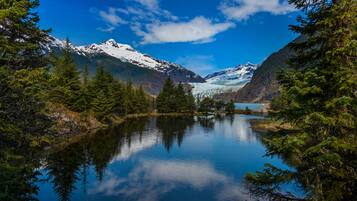 A serene lake surrounded by snow-capped mountains and dense forest.