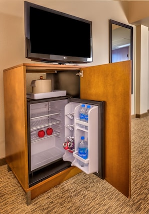 A compact refrigerator with a television above it, a water dispenser, and a small storage compartment. - Four Points by Sheraton Juneau (Juneau)
