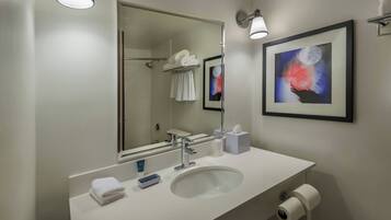 A modern bathroom with a large mirror, white sink, and towel rack.