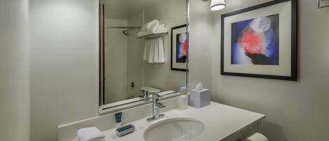 Un baño moderno con un espejo grande, lavamanos blanco y perchero.