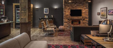 A modern living room with a stone fireplace, comfortable seating, and a flat-screen TV mounted on the wall.