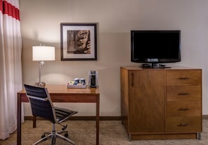 A hotel room with a desk, chair, television, cabinet, coffee maker, and framed artwork. - Four Points by Sheraton Juneau (Juneau)