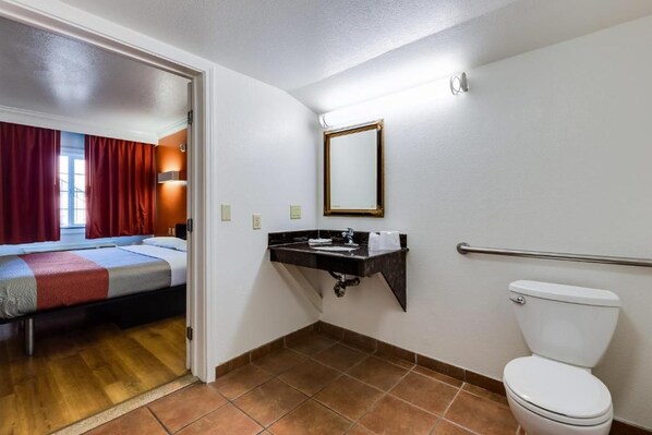 A hotel room with a bed, a bathroom with a toilet, and a sink.