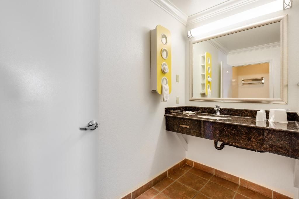 A bathroom with a sink, mirror, towel rack, and a door.