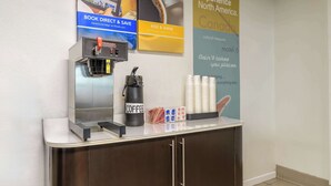 Una estación de café con una máquina de café, tazas y un cartel que promociona experiencias norteamericanas.