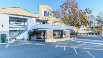 A modern hotel with a '6' sign, accessible entrance, and a parking lot.
