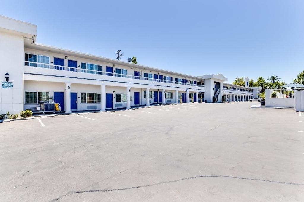 Un motel con una hilera de habitaciones, un estacionamiento y un edificio con una decoración azul y blanca.