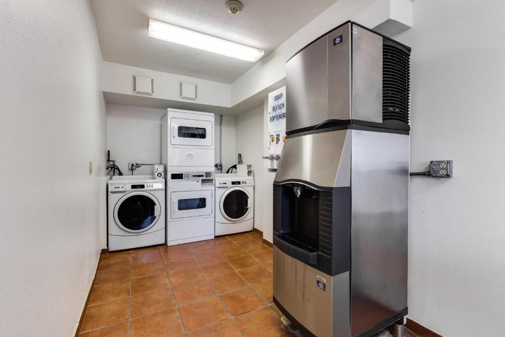 A laundry room with a stainless steel refrigerator, a washing machine, and a dryer.