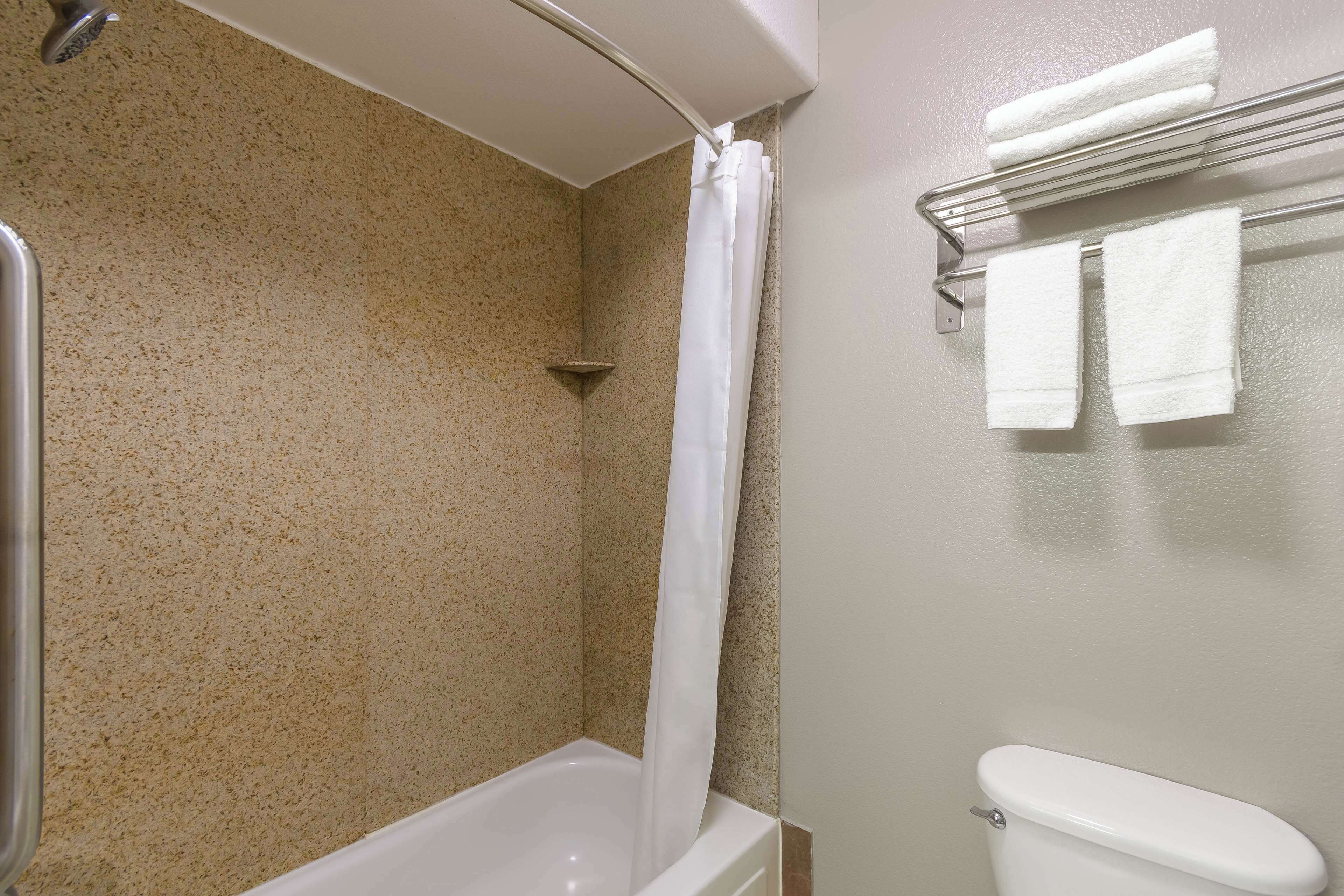 A bathroom with a shower, a toilet, and a towel rack with towels.