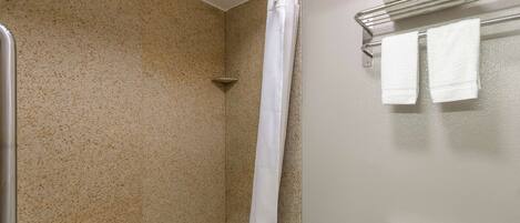 A bathroom with a shower, a toilet, and a towel rack with towels.