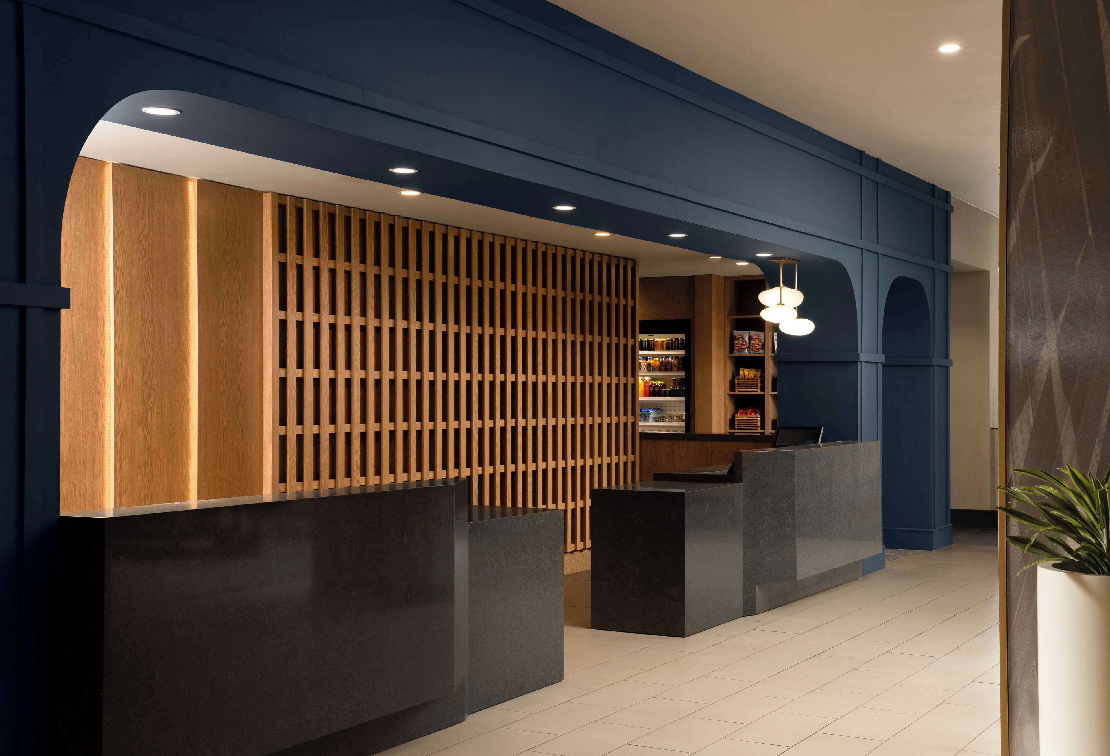 Un área de recepción con un separador de madera, un mostrador y una estantería con libros y revistas.