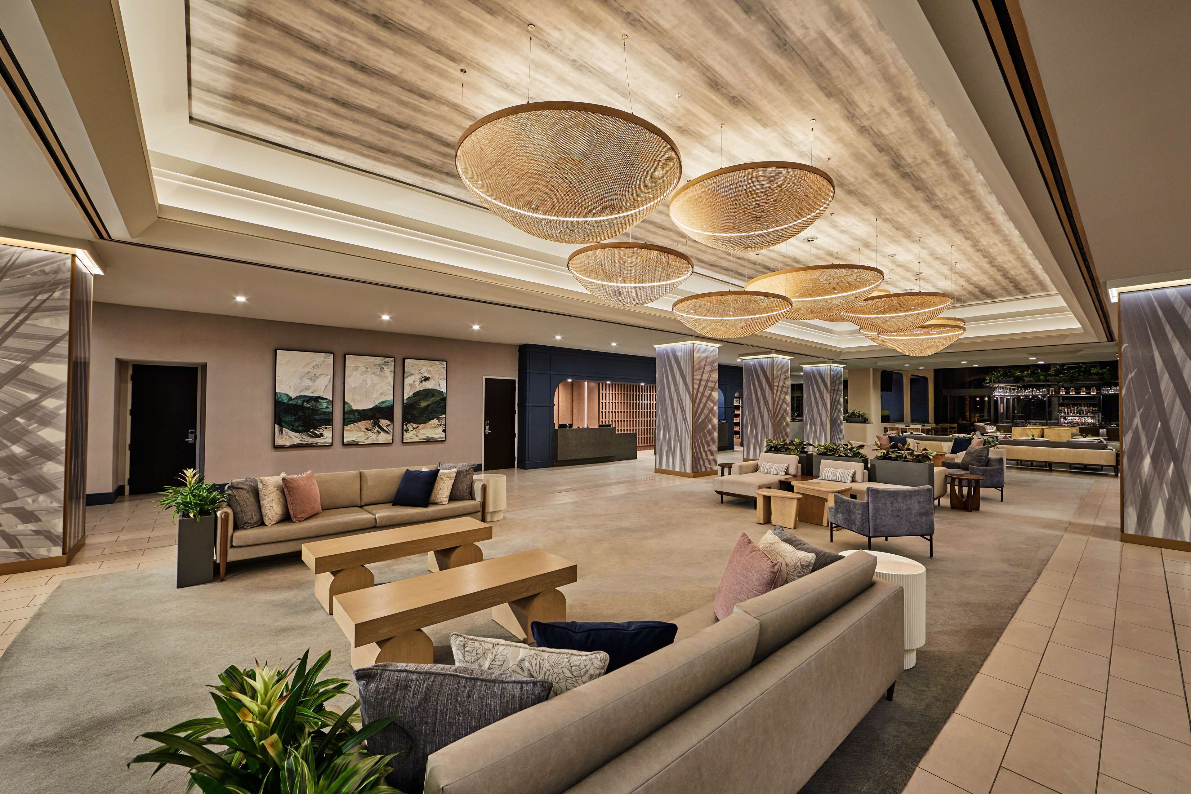 A spacious lobby with a modern design, featuring a reception desk, seating areas, and a bar.