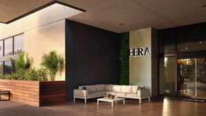 A modern lobby with a sectional sofa, a coffee table, and a wooden planter with plants. - Hotel Fera Anaheim, a DoubleTree by Hilton (Orange)