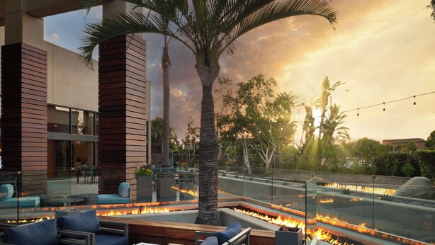 An outdoor seating area with fire pits, modern furniture, and a view of the sky. - Hotel Fera Anaheim, a DoubleTree by Hilton (Orange)