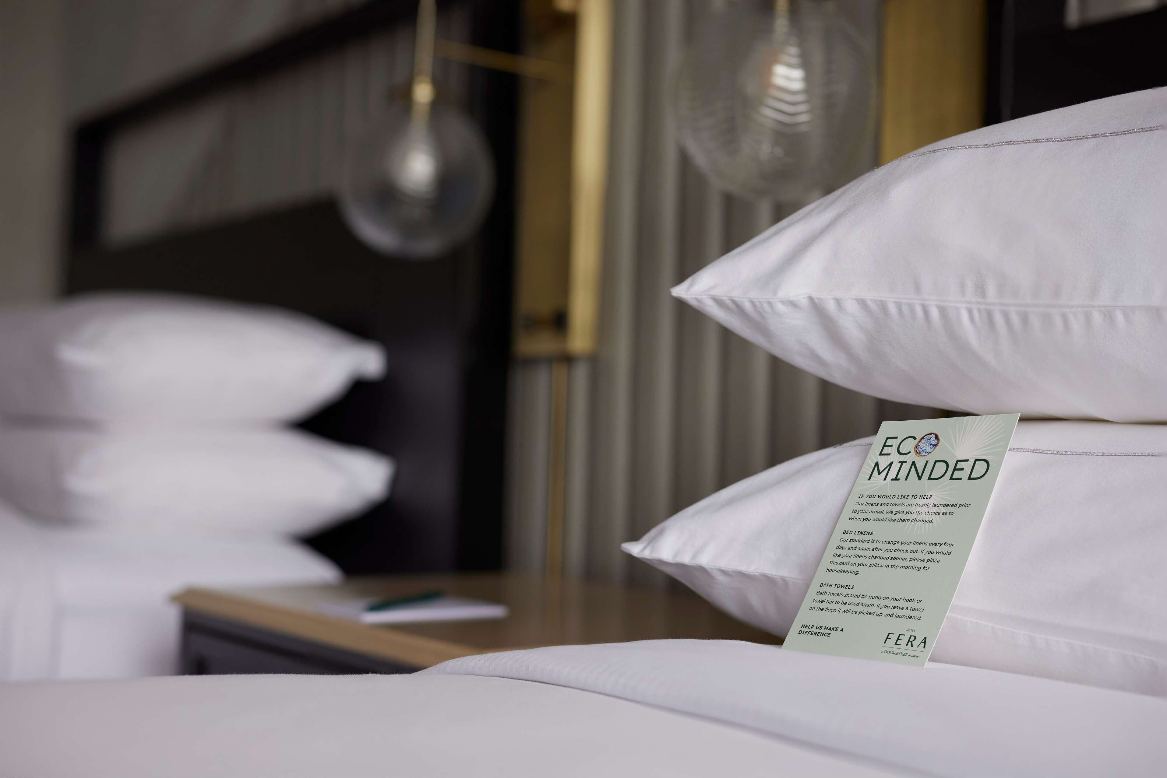 Una cama bien hecha con sábanas blancas y una señal en las almohadillas.