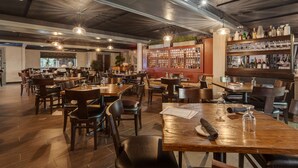A restaurant interior with wooden tables and chairs, a bar area with shelves of bottles, and a decorative wall. - The Hub Murray Hill, BW Premier Collection (New Providence)