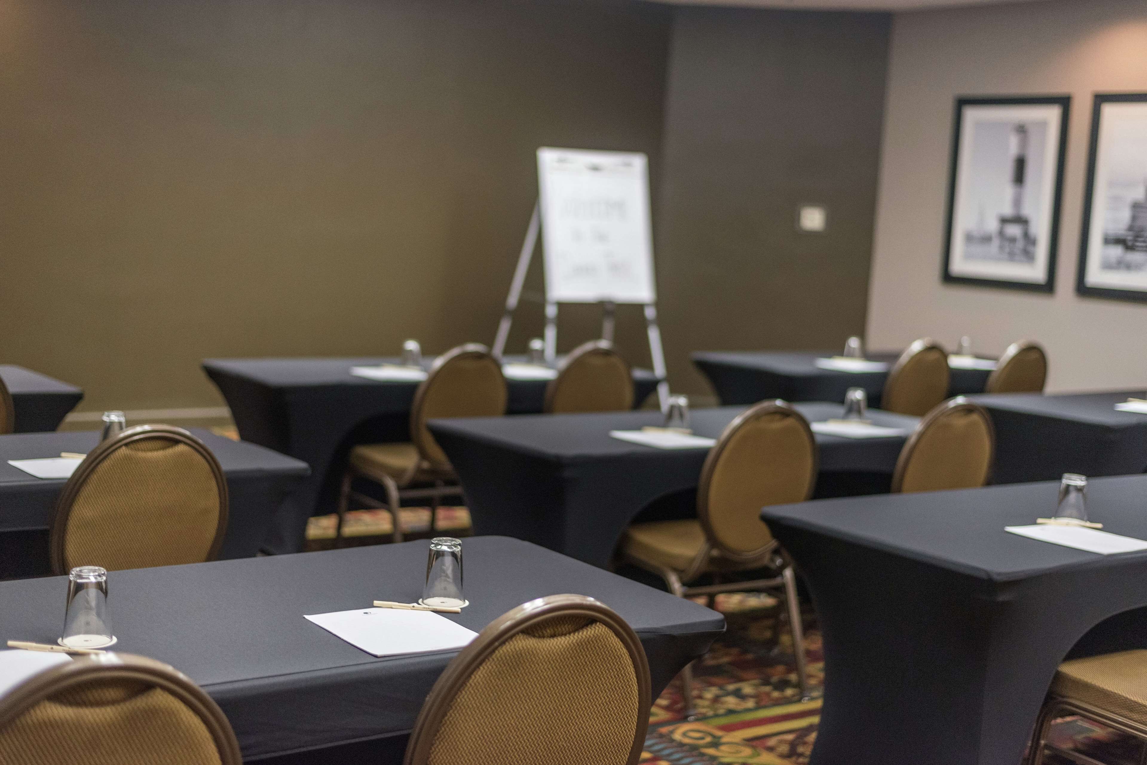 A conference room with tables, chairs, and a whiteboard.