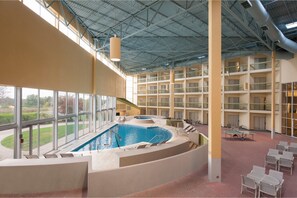 An indoor swimming pool with a view of the outdoors, surrounded by multiple balconies and a high ceiling. - DoubleTree by Hilton Holland (Holland)