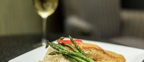 A plate of food with rice, asparagus, and a piece of fish, accompanied by a glass of white wine.