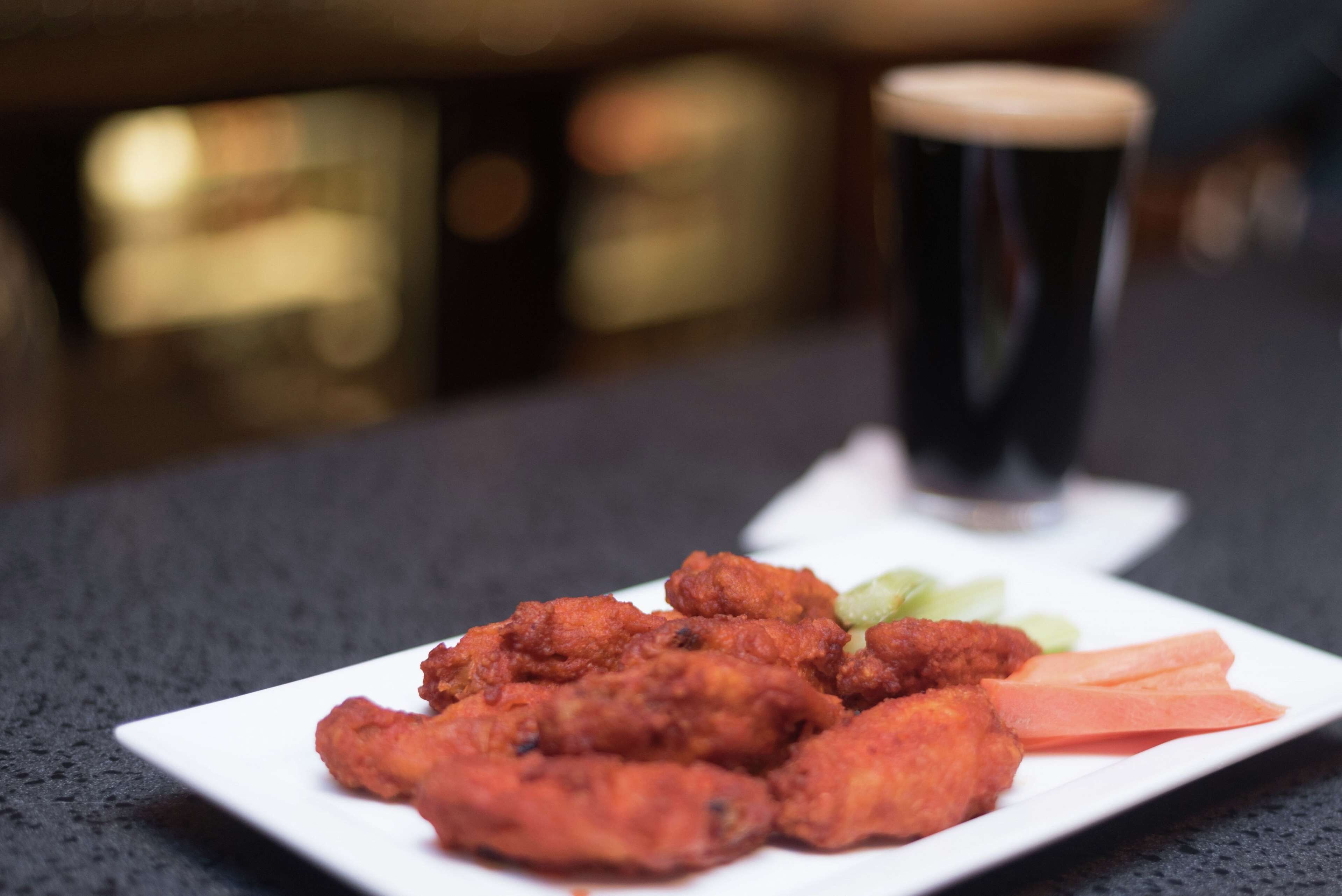 A plate of fried chicken with vegetables and a glass of dark beverage on a table.