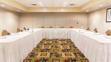 A conference room with a long table, chairs, and a patterned carpet.