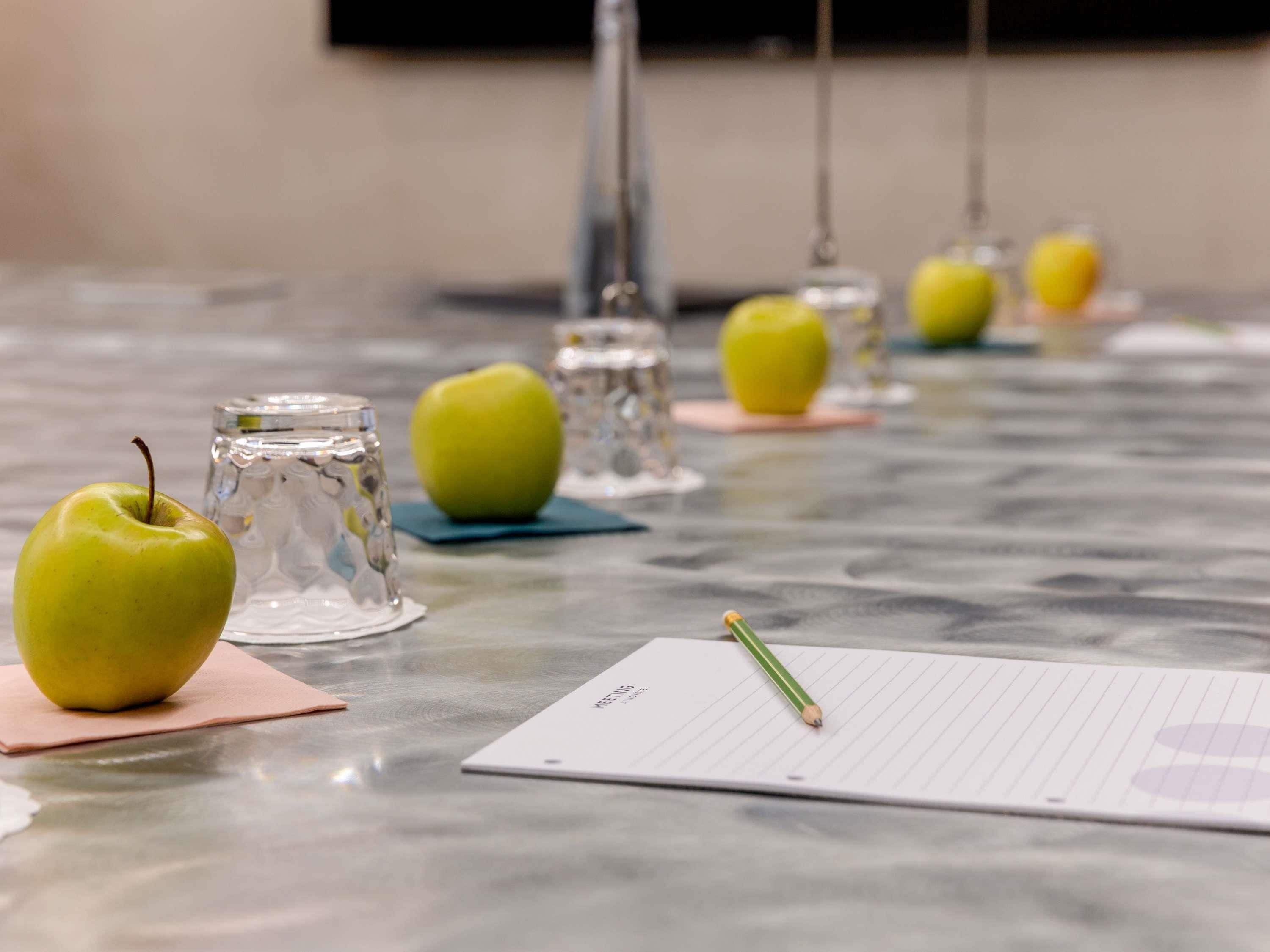 A table with apples, glasses, and a notepad.