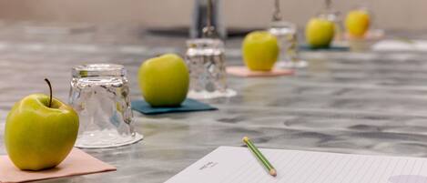 A table with apples, glasses, and a notepad.