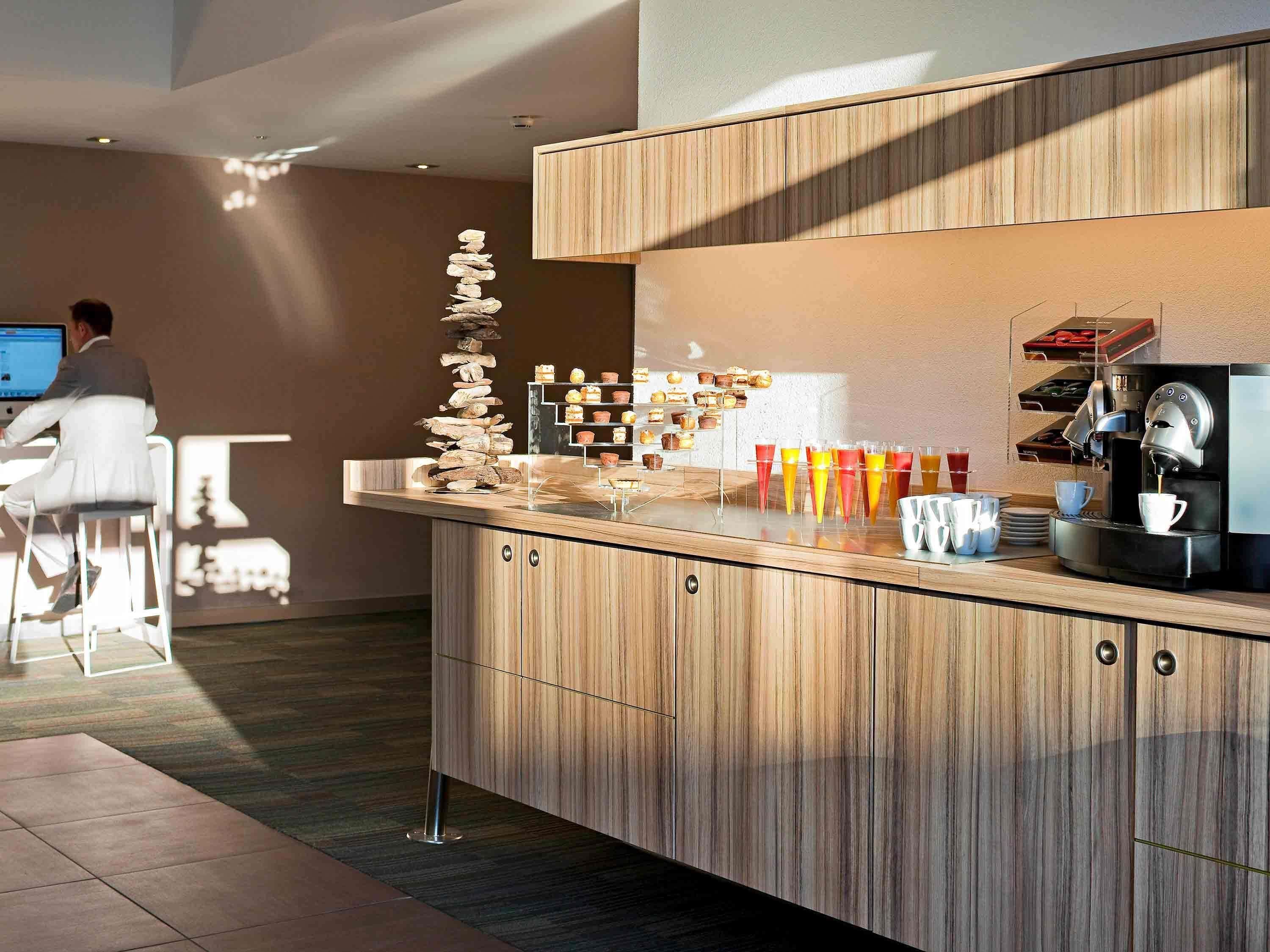 A modern kitchen with a wooden countertop, a coffee machine, and a stack of stones.