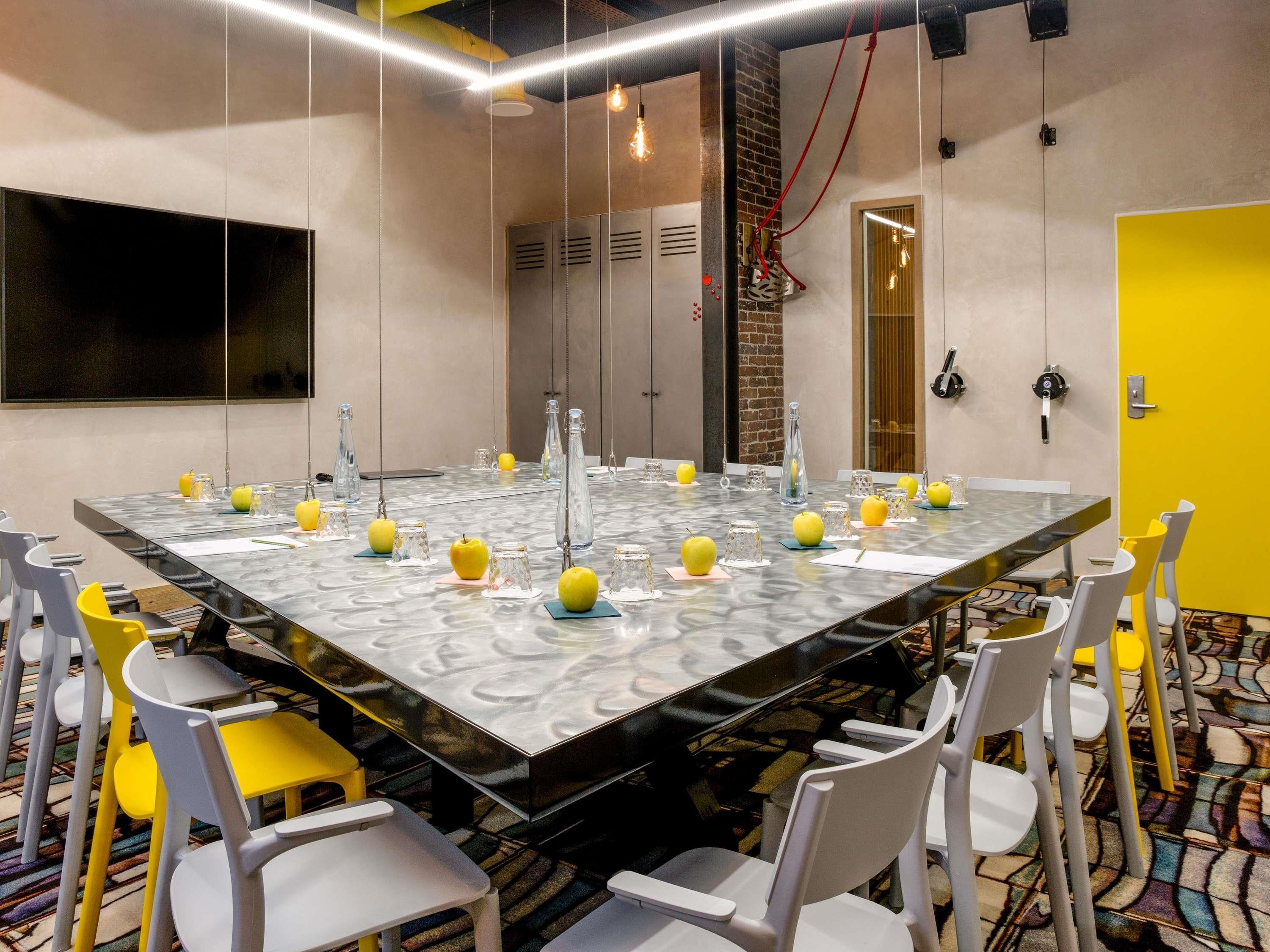 Une salle de conférence avec une grande table, des chaises et une porte jaune.