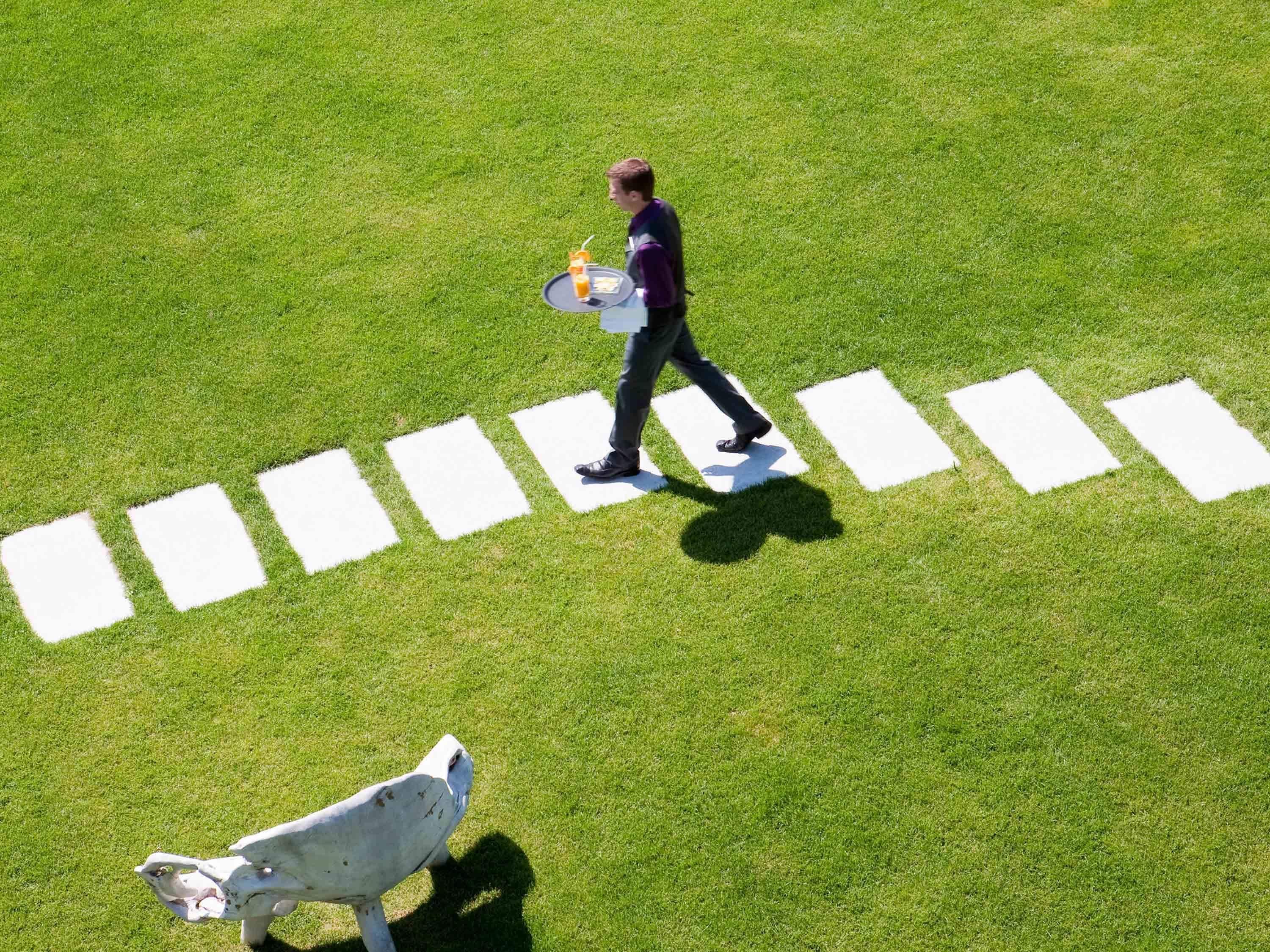 A person walking across a grassy area with white rectangular markings.
